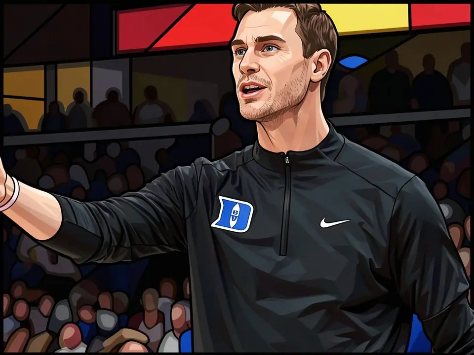 John Scheyer in Duke training gear with logo on chest, waving hand before stands