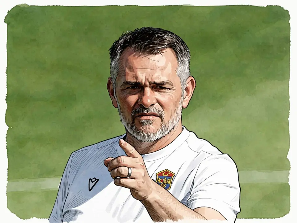 Willi Sagnol in einem weißen Trainingshemd steht auf einem grünen Feld und zeigt nach vorne.