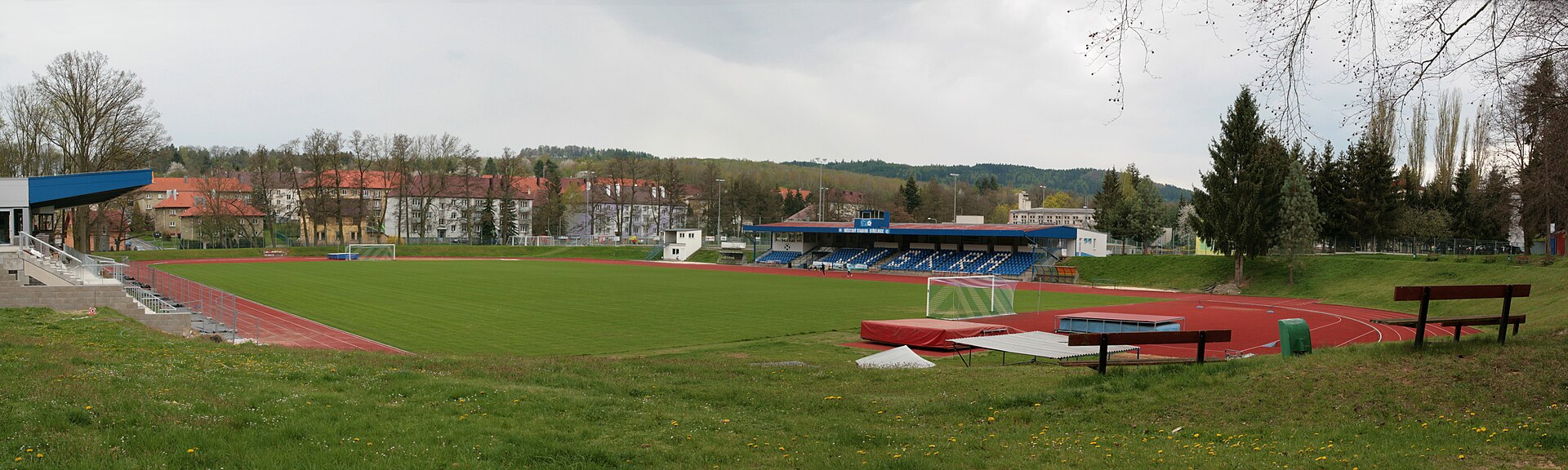 Město Domažlice. Fotbalový a atletický stadion TJ Jiskra Domažlice (Palackého čp. 379). Celkový panoramatický pohled ze severovýchodního rohu areálu.