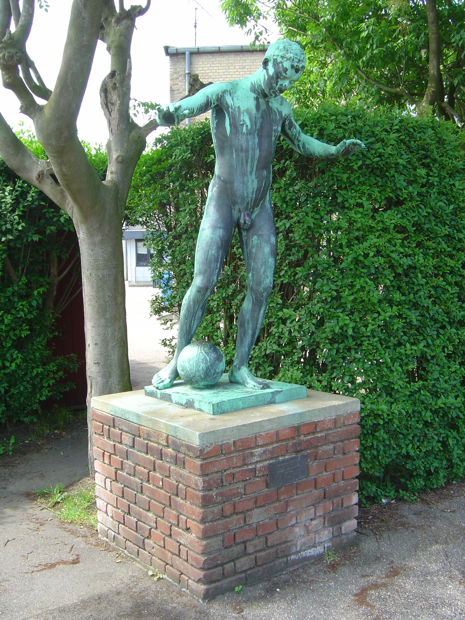 Sundby Idrætspark , the statue from 1903 named En fodboldspiller by Carl Mortensen (1861—1945) is located in the western section of Opvisningsbanen on Amager, Copenhagen. Seen from northeast side of the statue.