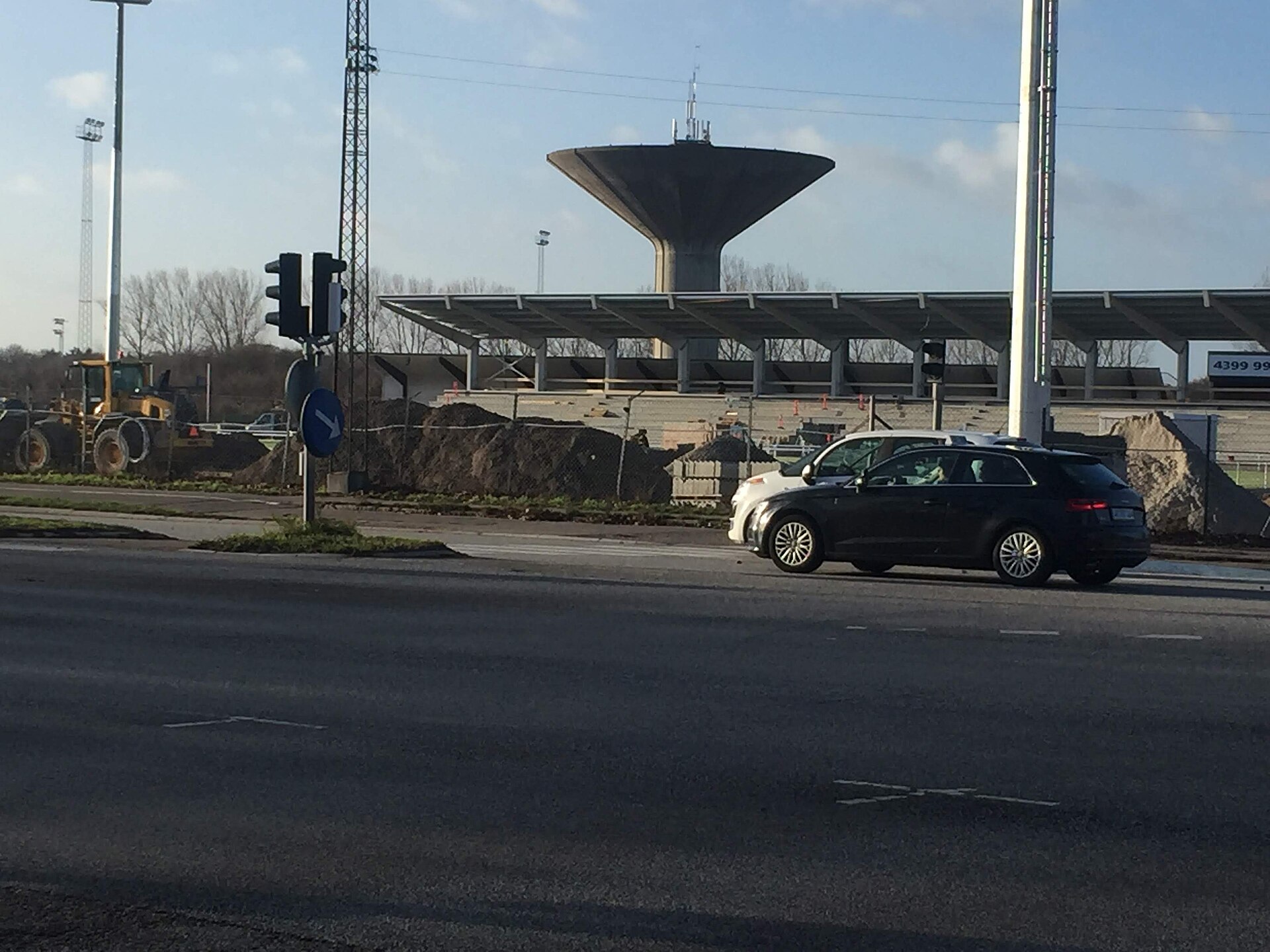 Køge Stadium during reconstruction in December 2018. In the background is the water tower in Køge , and just behind the new stand, the remaining part of the old stadium is visible
