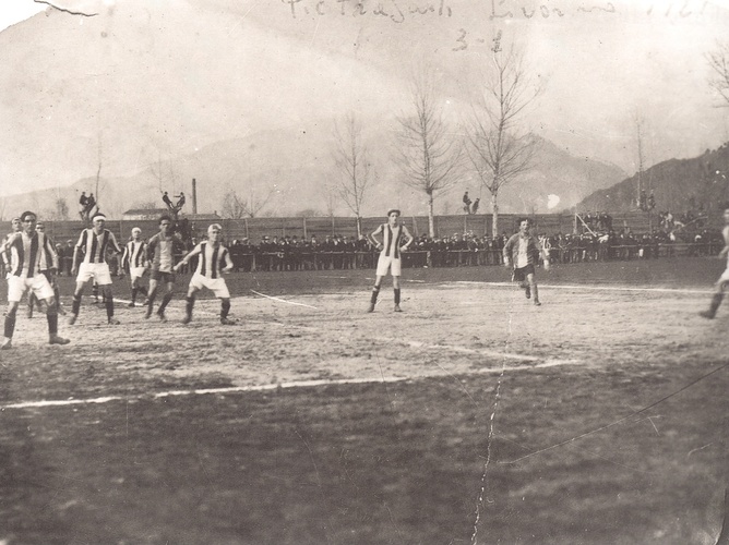 Football game. The writing says "Pietrasanta – Livorno 1921 // 3–1". They were not in the same league, so perhaps this is a cup game or a friendly game. It may be at Viale Marconi stadium, opened 27 June (year?). The first game played was on 8 October 1922 (not 1921?) between Audace Livorno and Piet