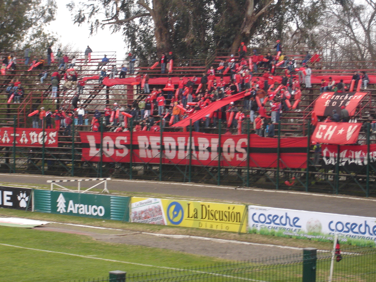 Fotografía de hinchas de Club Deportivo Ñublense en el antiguo Estadio Municipal Nelson Oyarzún Arenas, 2007, durante un partido de fútbol entre Club Deportivo Ñublense y Lota Schwager.