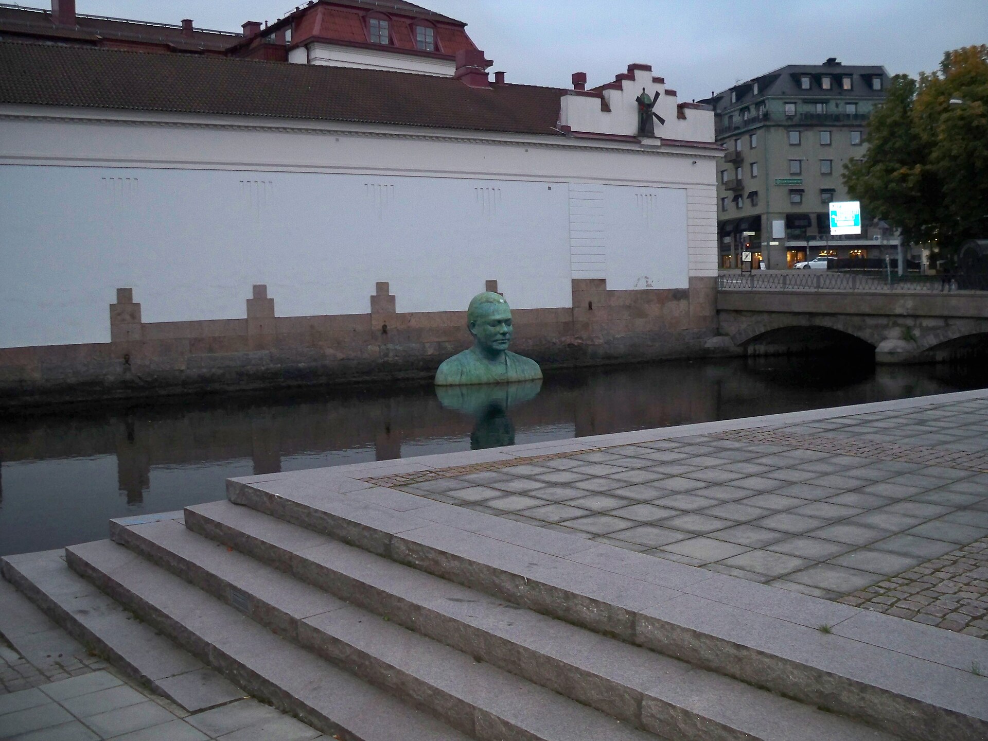 The bronze-bust Bodhi (2004) by the Swedish sculptor Fredrik Wretman in the watery and stony environment of Borås, Sweden.