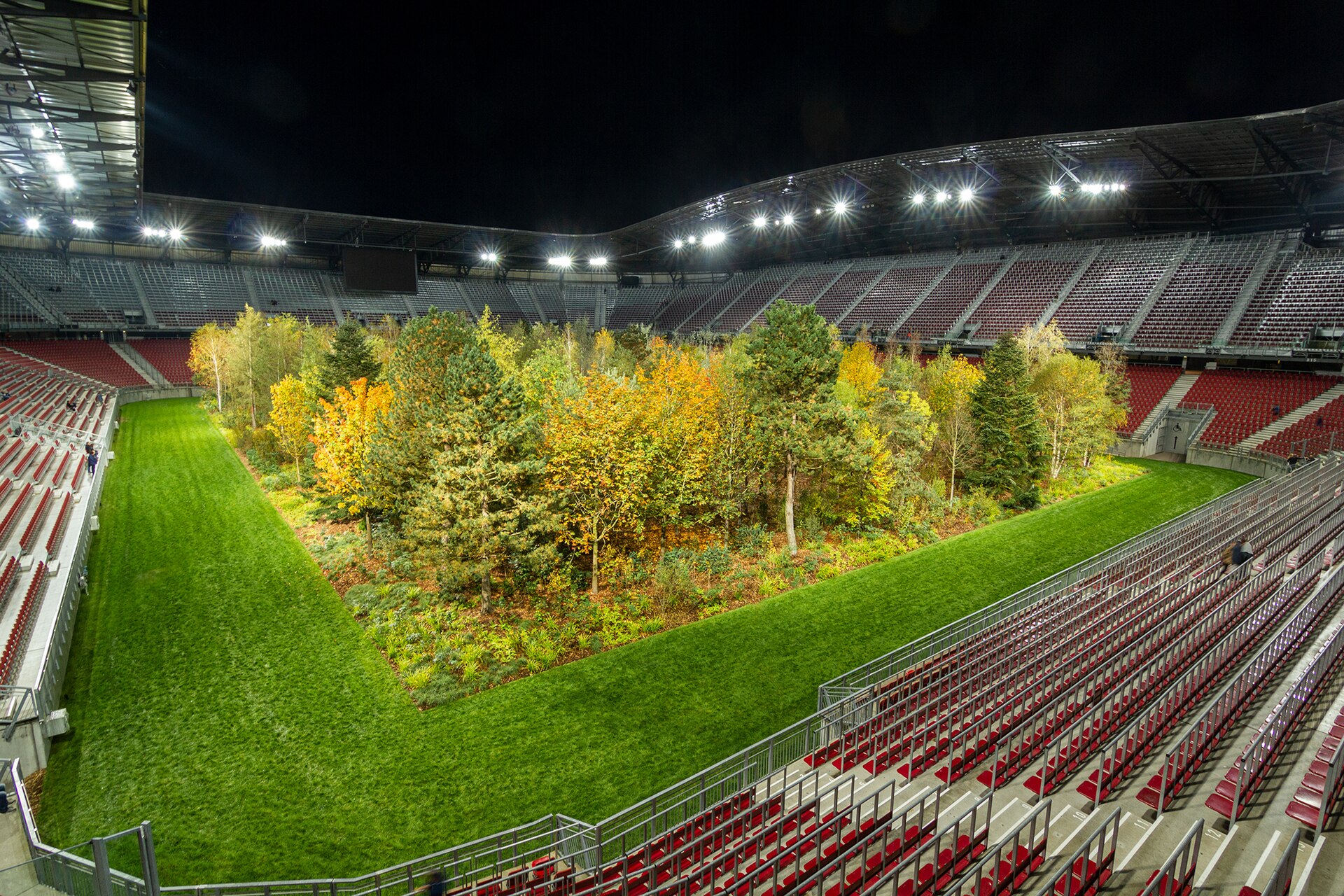 For Forest. The Unending Attraction of Nature” was a temporary art intervention by Klaus Littmann in the football arena of Klagenfurt, Austria. The project was based on the pencil drawing “The Unending Attraction of Nature” by Max Peintner from the 1970s, which shows a small forest in a crowded sta