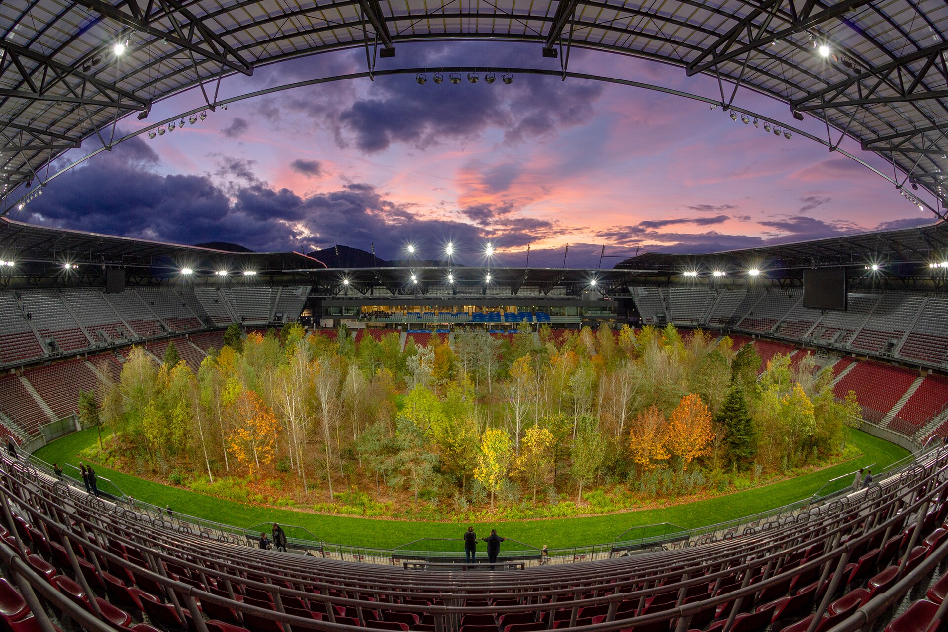 For Forest. The Unending Attraction of Nature” was a temporary art intervention by Klaus Littmann in the football arena of Klagenfurt, Austria. The project was based on the pencil drawing “The Unending Attraction of Nature” by Max Peintner from the 1970s, which shows a small forest in a crowded sta