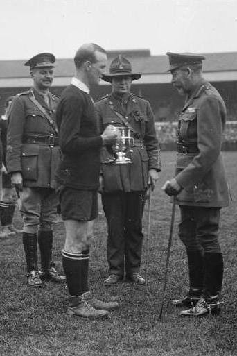 King George V presents a cup to the captain of the winning New Zealand Services Rugby Team, London, Apr 1919. Reference number: 1/2-014210-G 1 b&w original negative(s). Dry plate glass negative 4 x 5 inches. Horizontal image. Part of Royal New Zealand Returned and Services’ Association: New Zealand