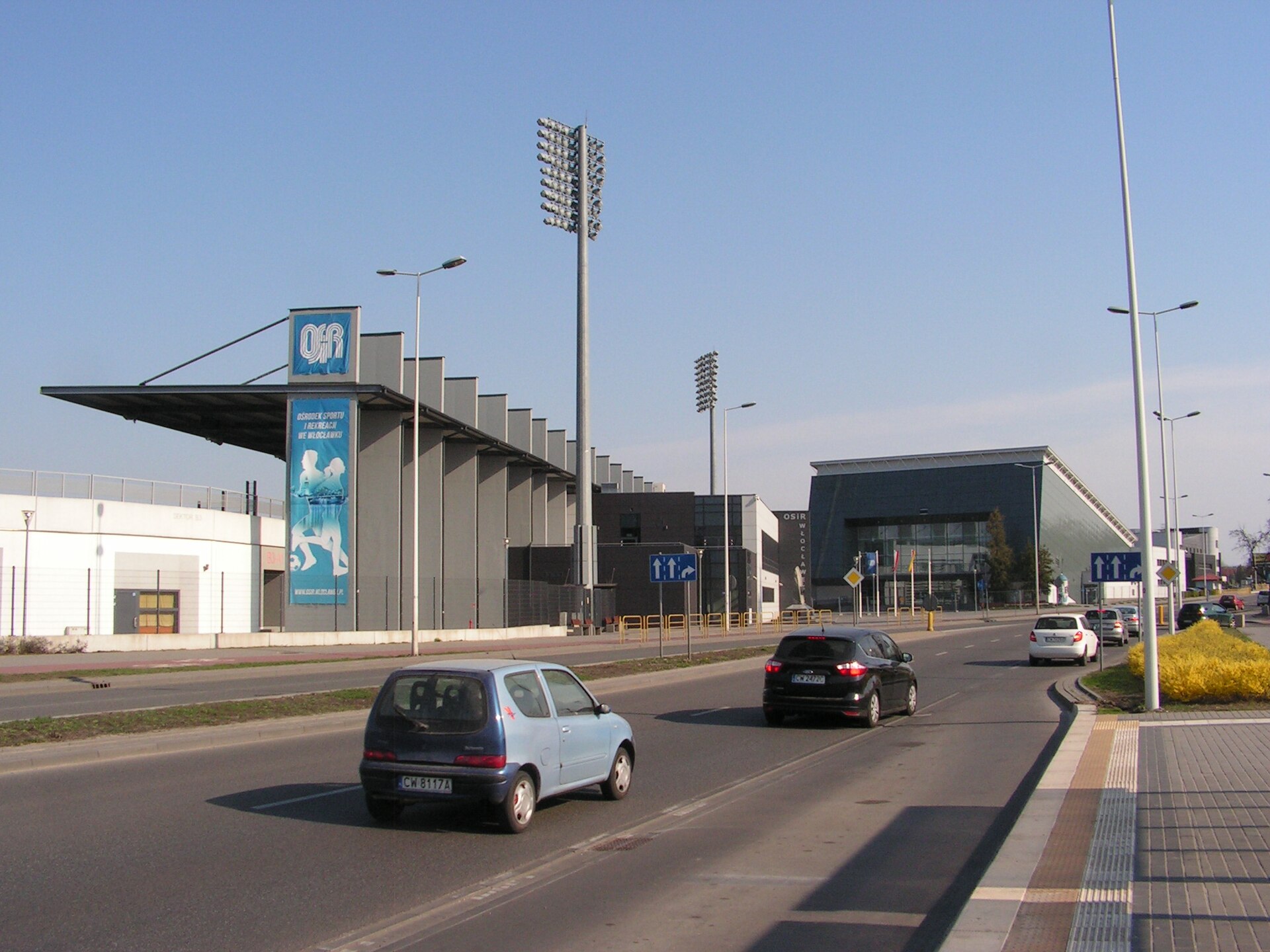 Chopin Avenue in Włocławek. On the foreground there is a OSiR (Ośrodek Sportu i Rekreacji - Sport and Recreation Centre) football-athletics stadium, rebuilt from 2011 to 2014 year. On the background there is a OSiR Hall, rebuilt from 2017 to 2018 year.