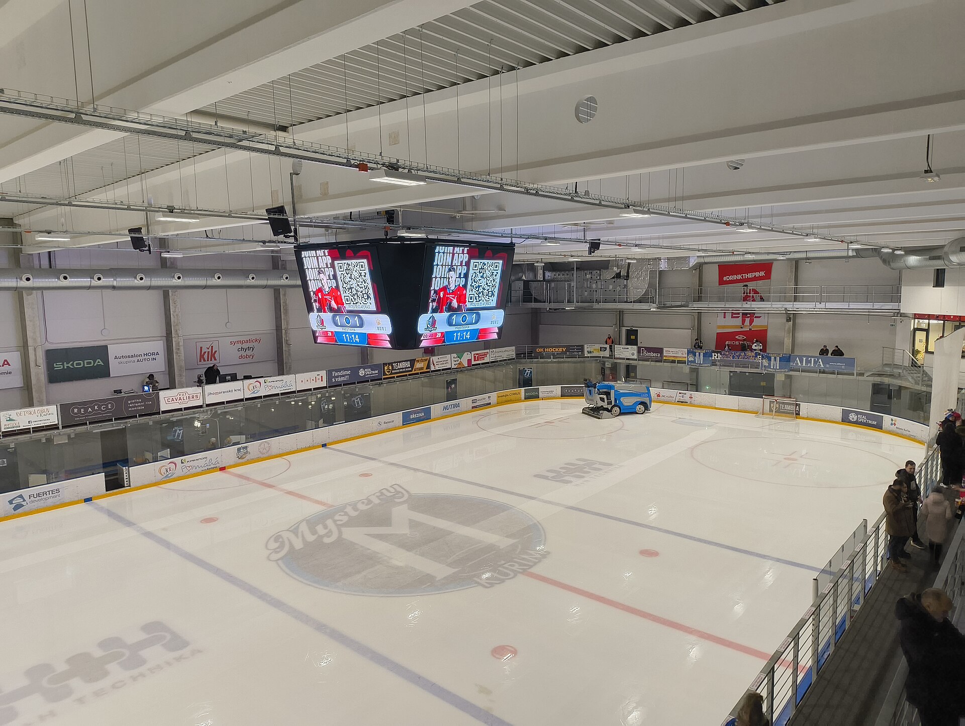 Zimní stadion Kuřim – Fotografie z přestávky mezi 1. a 2. třetinou zápasu 13. kola Univerzitní ligy ledního hokeje mezi VUT Cavaliers Brno a HC MUNI (2025/2026); Fotografováno z 2. nadpodlaží, z konce tribuny