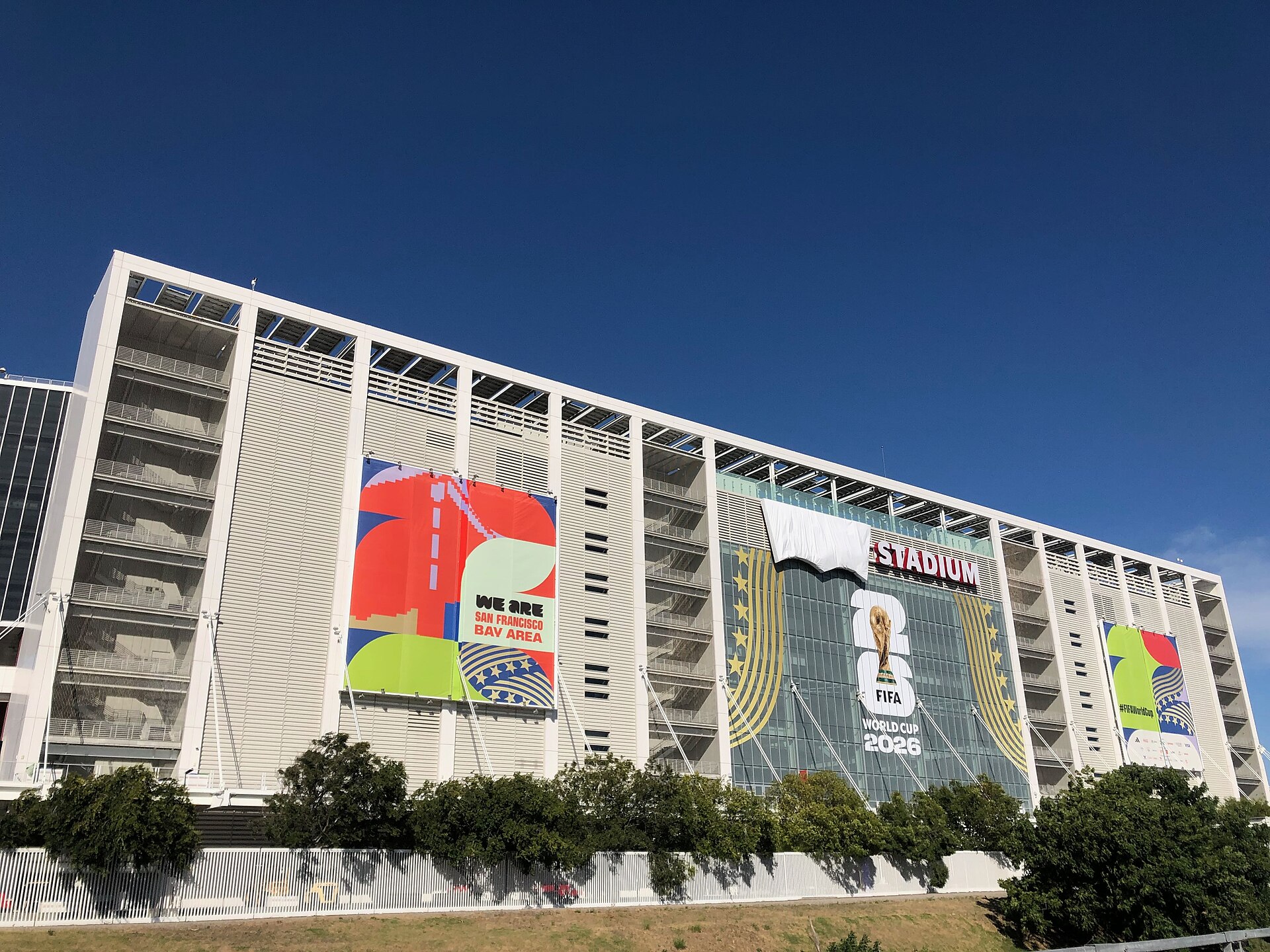 Levi’s Stadium, temporarily rebranded as San Francisco Bay Area Stadium for the 2026 FIFA World Cup, as seen from the west along San Tomas Aquino Creek Trail. “We Are San Francisco Bay Area” billboards adorn the back side of SAP Tower. The Levi’s logo in the stadium sign is covered in a white tarp,