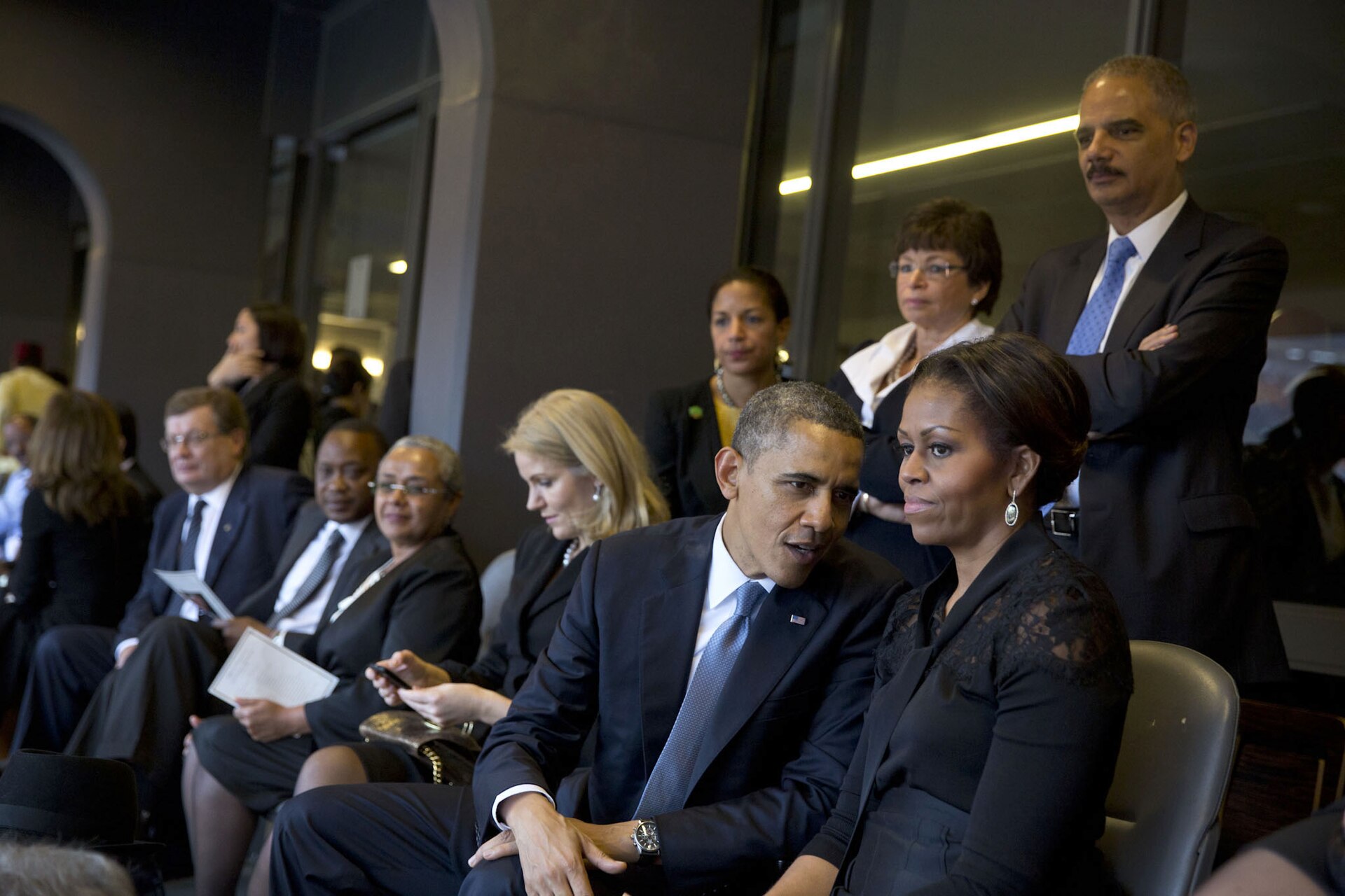 President Obama talks with the First Lady with other world leaders seated nearby. In the background are National Security Advisor Susan E. Rice, Valerie Jarrett, and Attorney General Eric Holder. (Official White House Photo by Pete Souza)